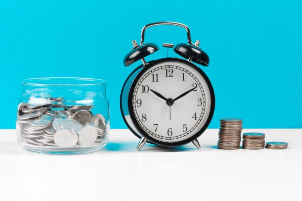 Alarm clock and money coins on the table. Close up.