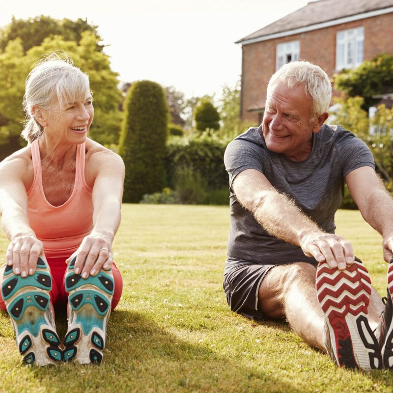 healthy senior couple exercising in garden togethe PXAP73D min